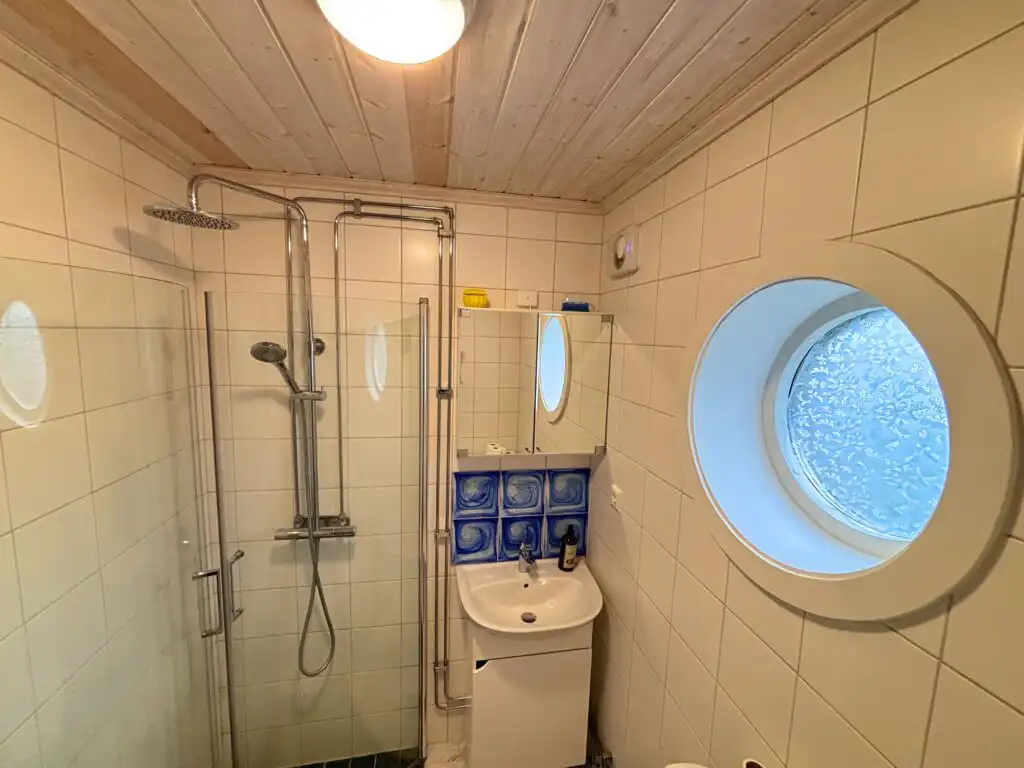 Badezimmer im Ferienhaus Hus Kråkelund mit Dusche und Bullaugenfenster