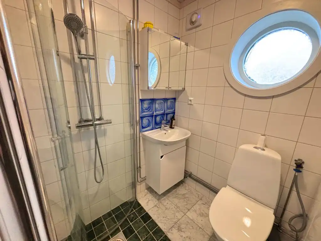 Badezimmer im Ferienhaus Hus Kråkelund mit Dusche und Bullaugenfenster