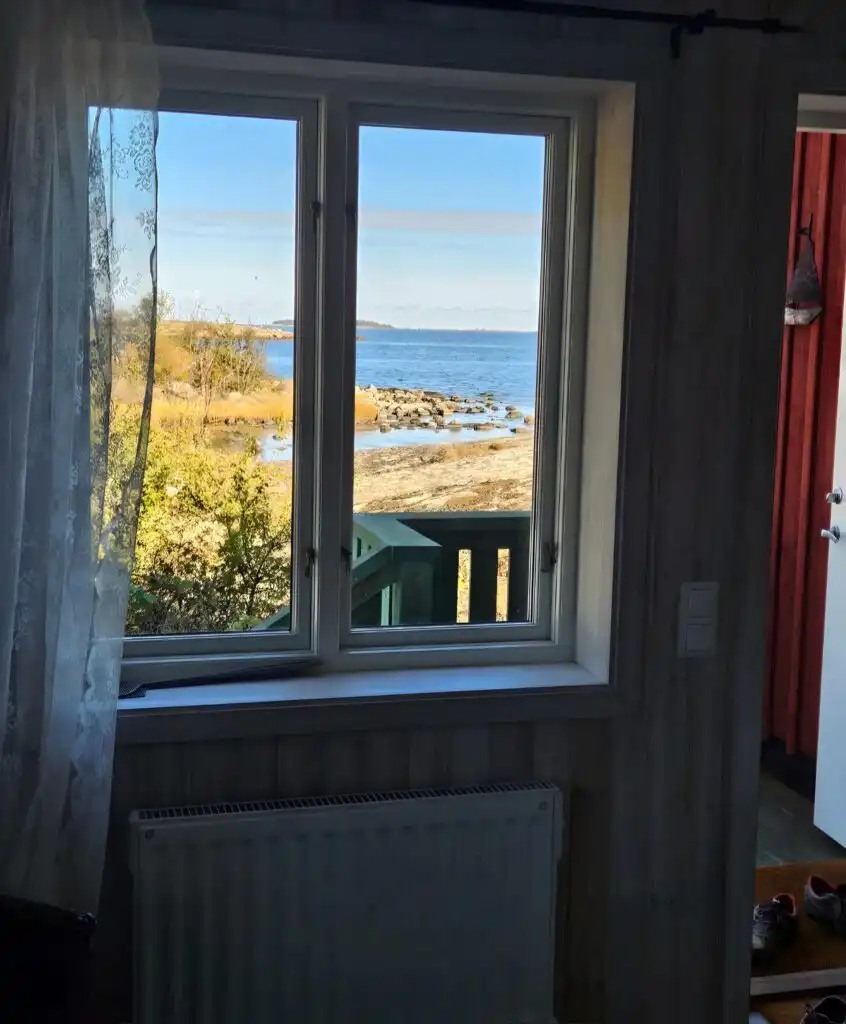 Schlafzimmer mit Fensterblick auf die Küstenlandschaft bei Hus Kråkelund