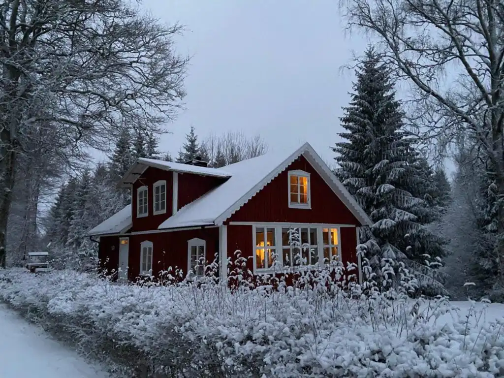 Verschneites rotes Ferienhaus Torsholma Skolhus im Wald von Småland – idyllischer Winterurlaub in Schweden