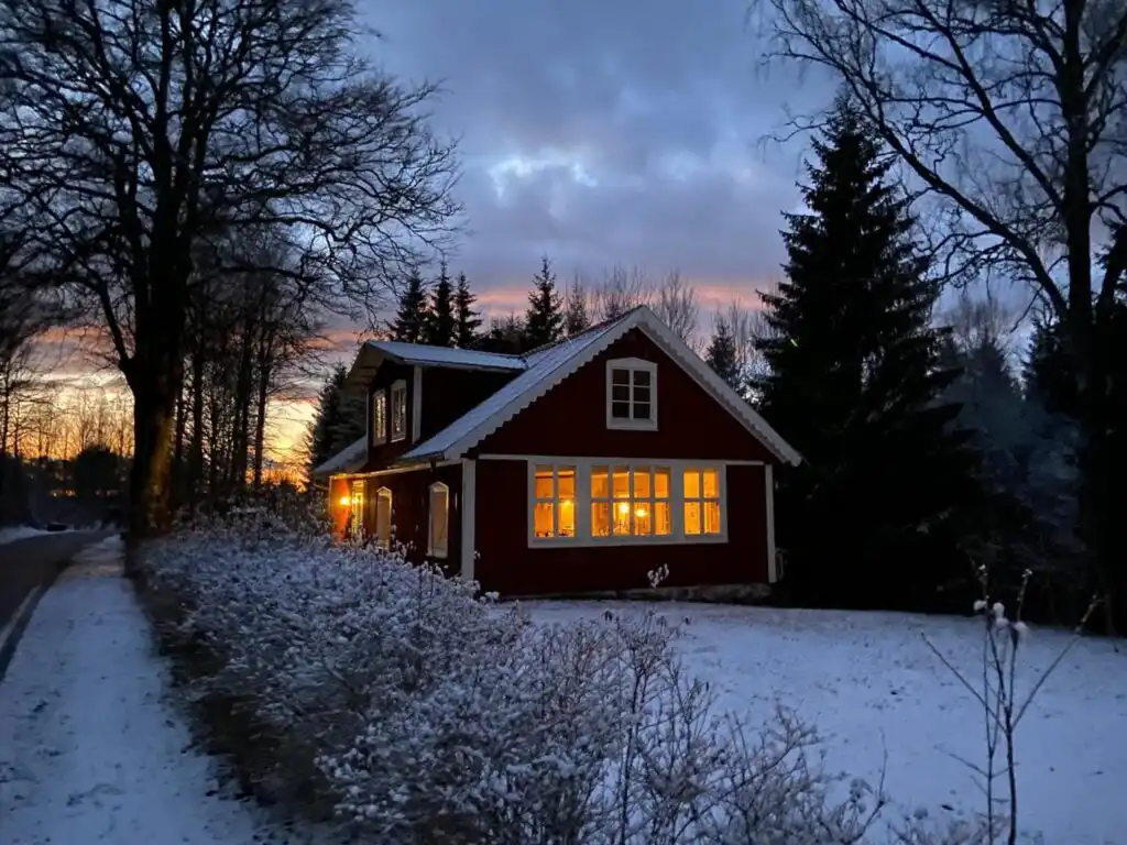 Beleuchtetes Ferienhaus Torsholma Skolhus am Abend im Winter – gemütliche Atmosphäre in der Natur von Småland
