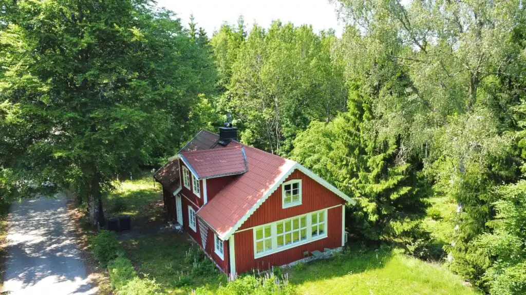 Vogelperspektive auf das rote Ferienhaus Torsholma Skolhus umgeben von Wäldern in Småland – ruhige Lage in der Natur