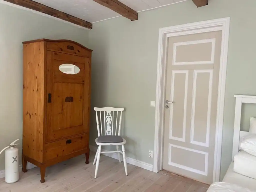 Helles Schlafzimmer im Ferienhaus Torsholma Skolhus in Småland mit Holzbalken und klassischer Einrichtung im historische