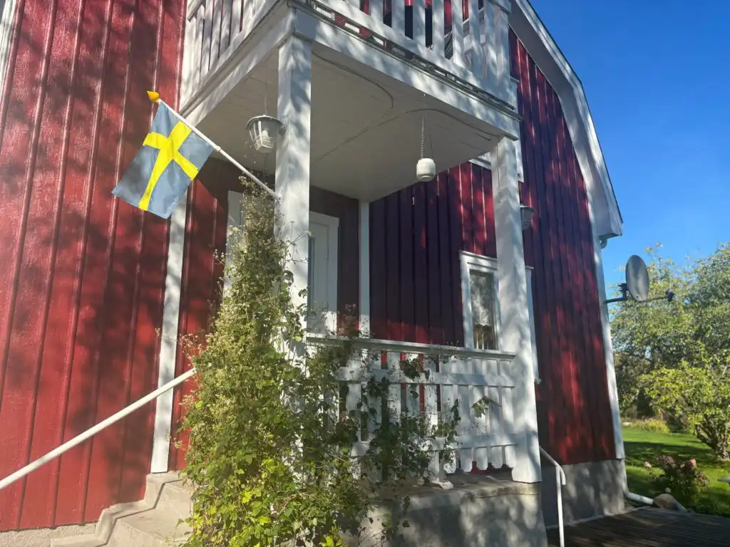 Eingangsbereich von Hus Brobacka in Brobacka – traditionelles Schwedenhaus mit schwedischer Flagge