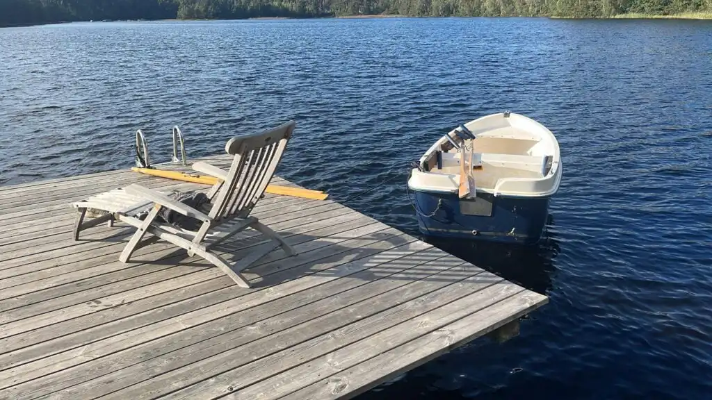 Steg mit Liegestuhl und Ruderboot am See Yasjön