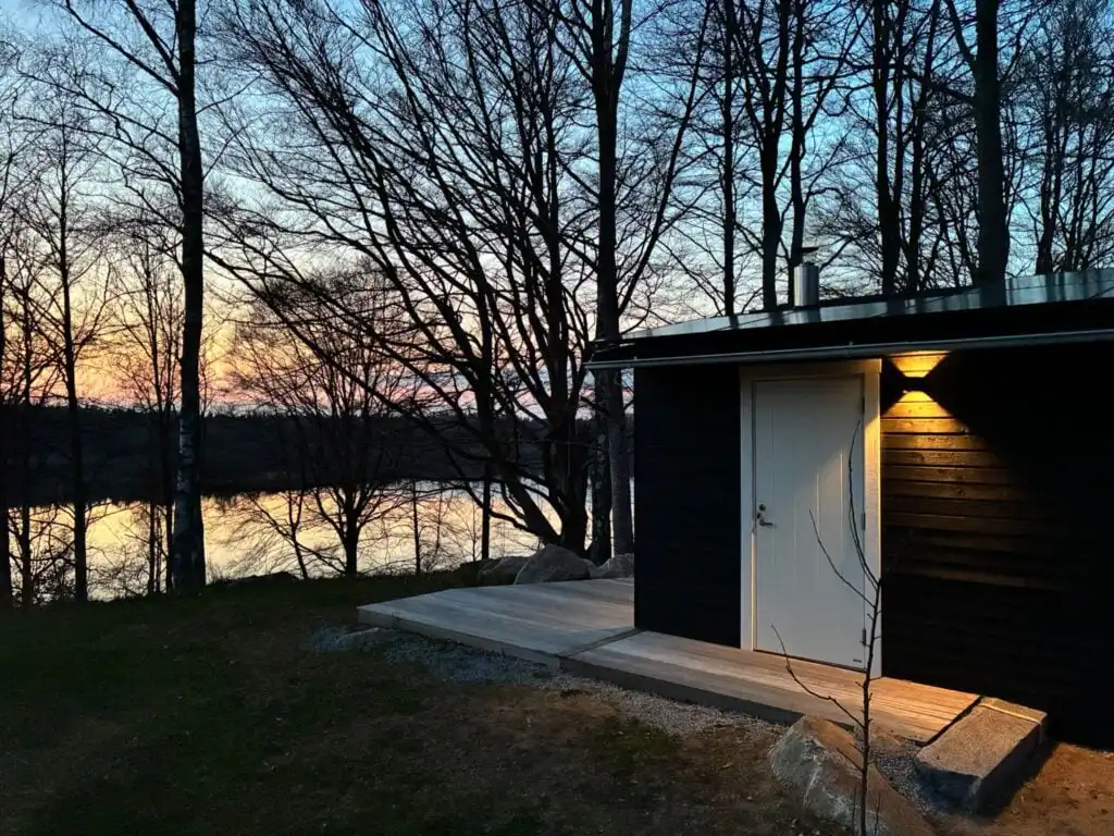 Saunahaus im Wald am Abend mit Beleuchtung nahe dem Ferienhaus