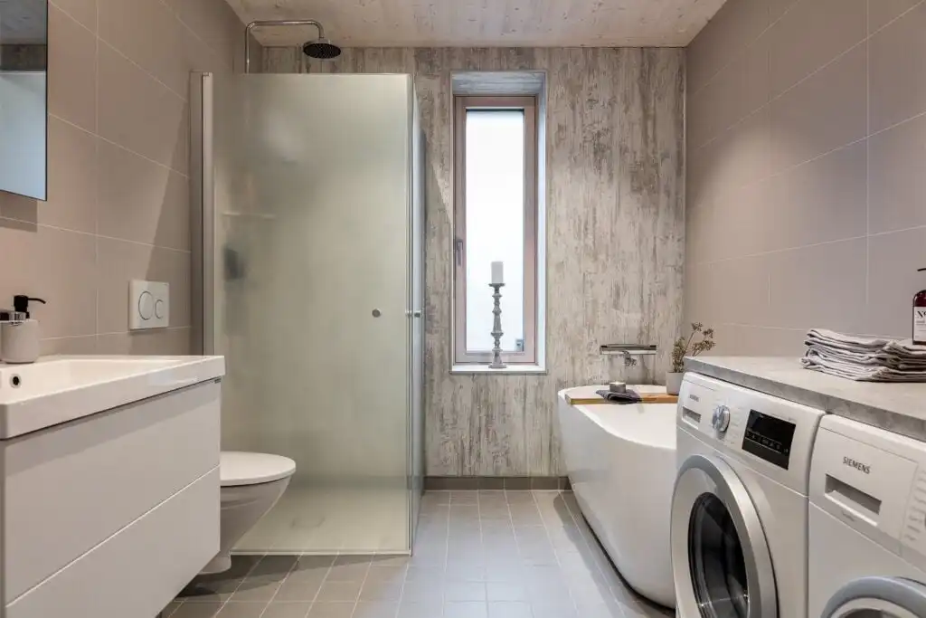 Modernes Badezimmer mit Waschmaschine und Trockner im nachhaltigen Ferienhaus CIRCUITUS