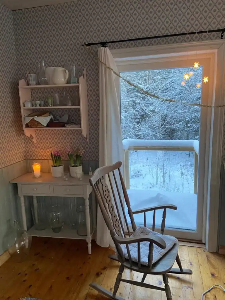 Wohnraum mit klassischem Holzofen im Ferienhaus Torsholma Skolhus in Småland – gemütlicher Rückzugsort im Schwedenurlaub