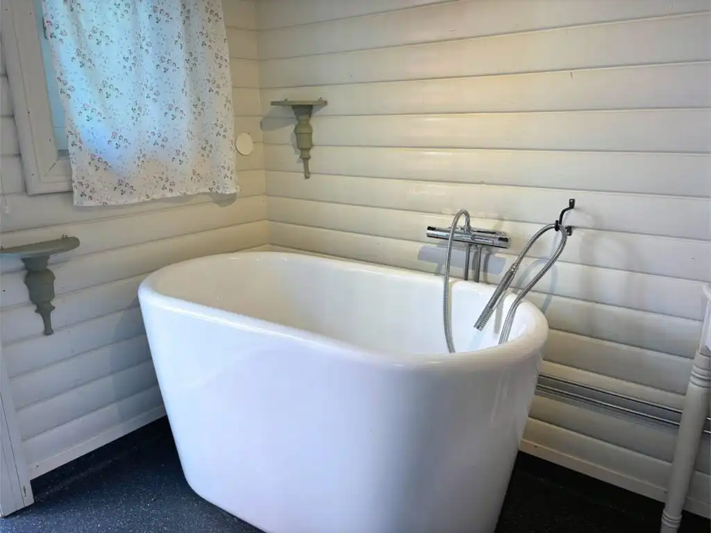 Badezimmer mit freistehender Badewanne im Ferienhaus Hus Bubbarbso – modernes Bad mit Blick in die Natur