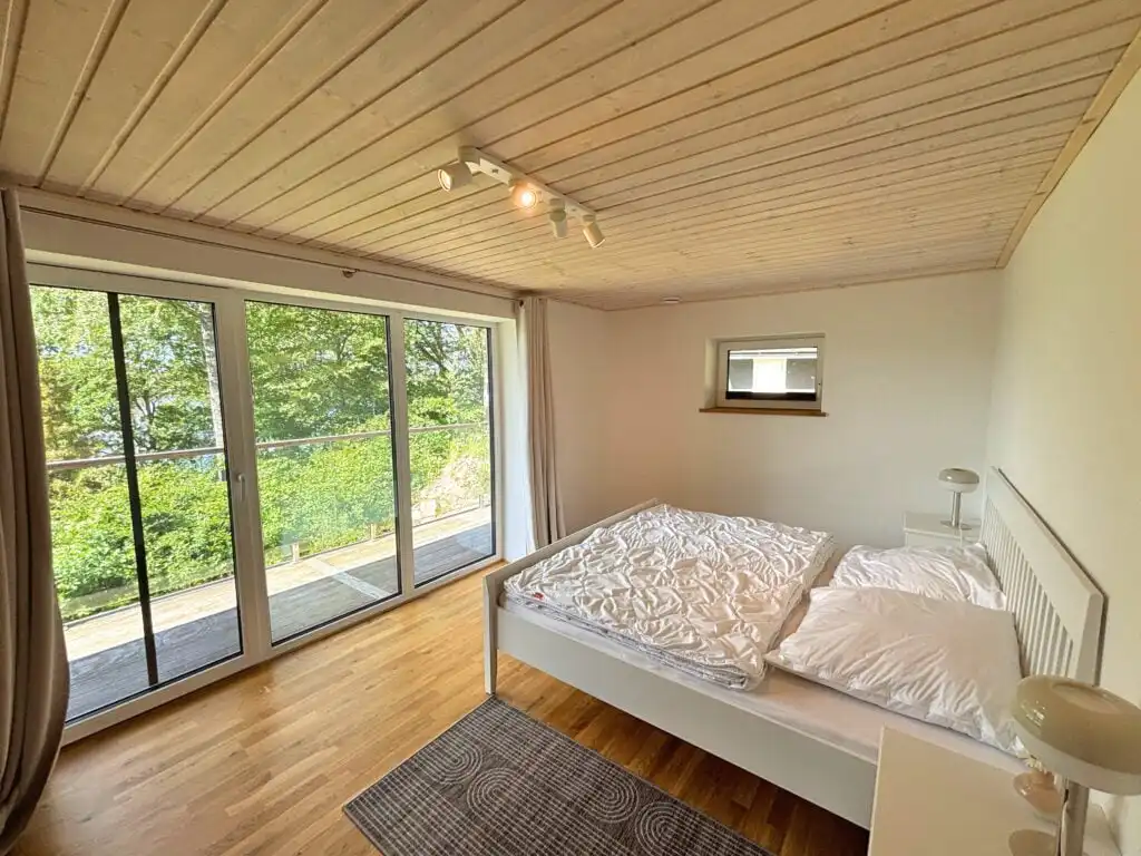 Schlafzimmer mit großen Fenstern und Naturblick