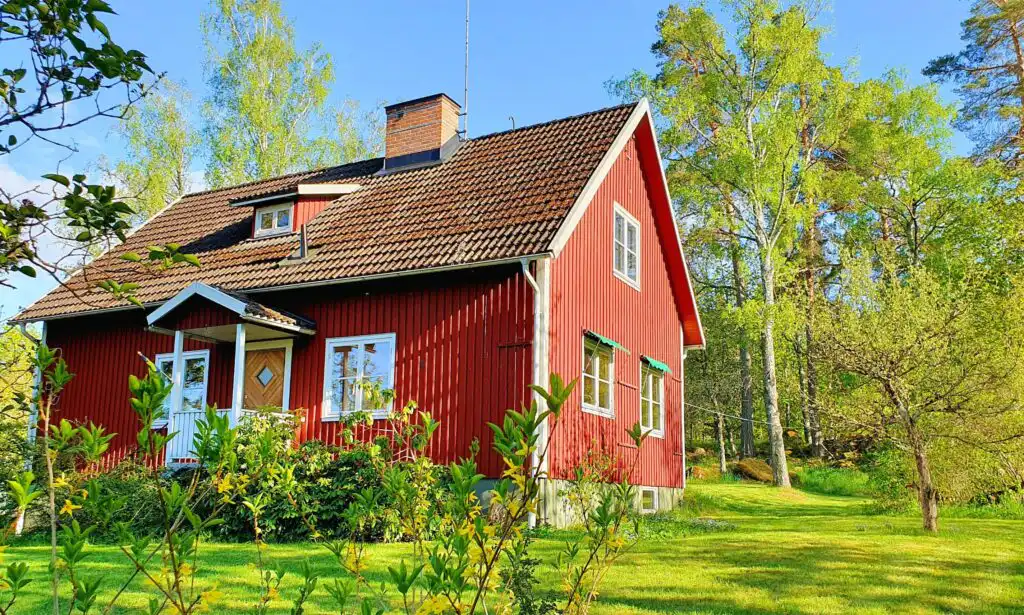 Rotes Schwedenhaus Hus Fågelfors umgeben von grüner Natur