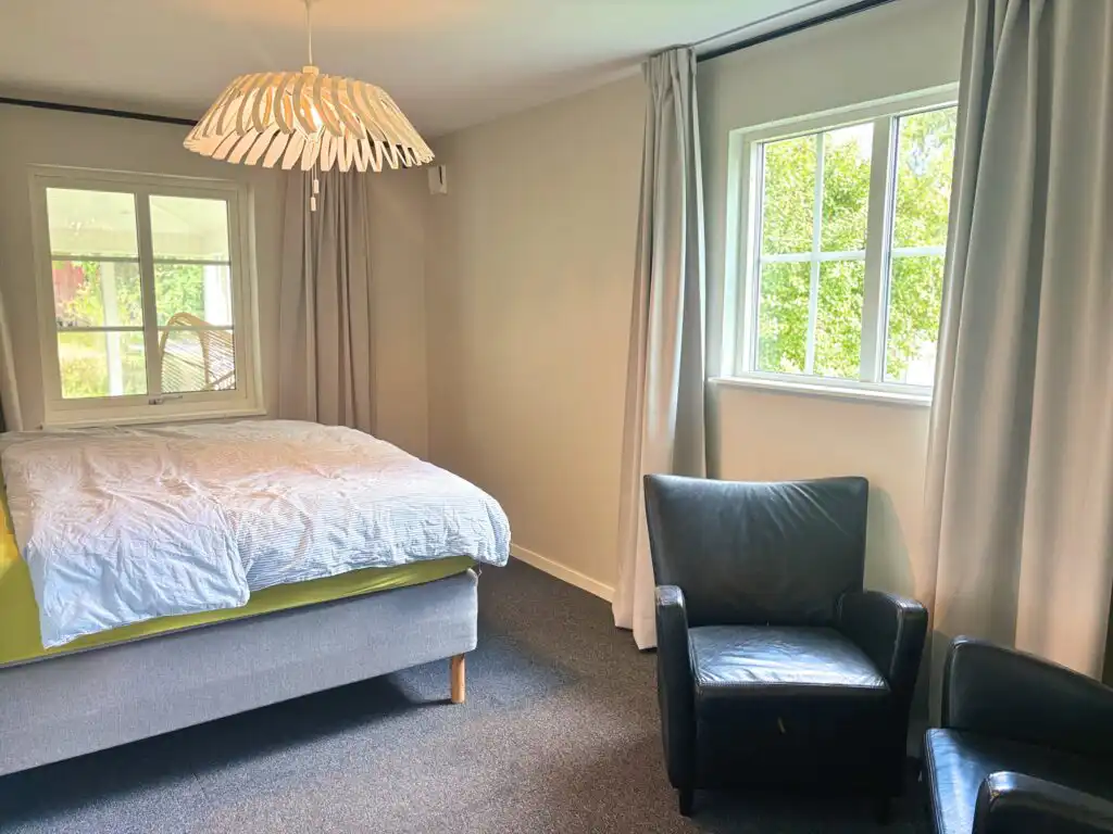 Helles Schlafzimmer mit Doppelbett und Gartenblick im Linnéagården