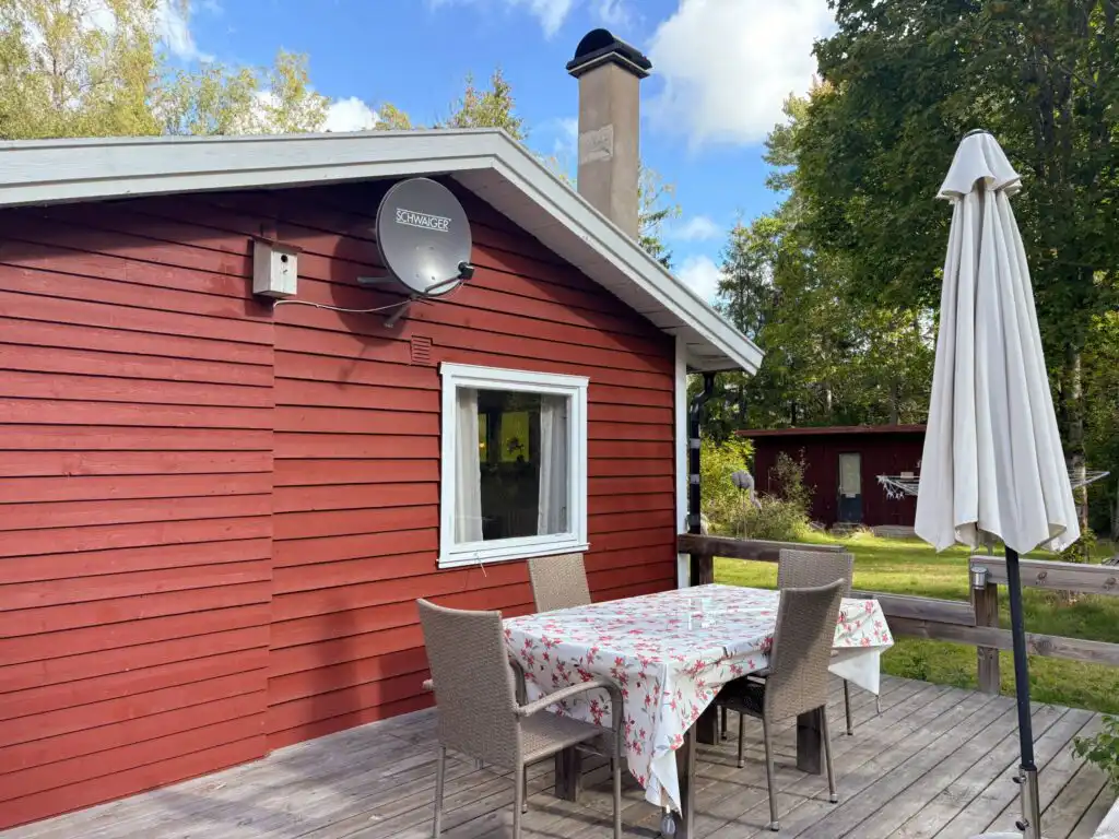 Terrasse mit Gartenmöbeln am roten Ferienhaus Hus Älmtamåla